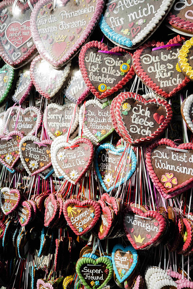 Zahlreiche bunt verzierte Lebkuchenherzen mit typischen Oktoberfest-Botschaften an einem Verkaufsstand.