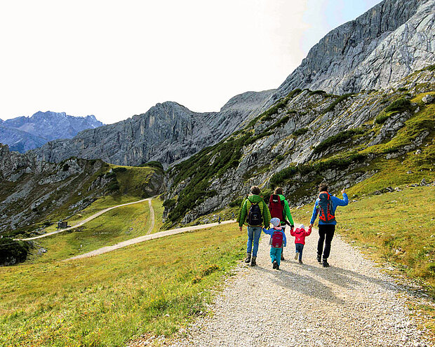 Familie von hinten, die in den Garmischer Bergen bergab wandert