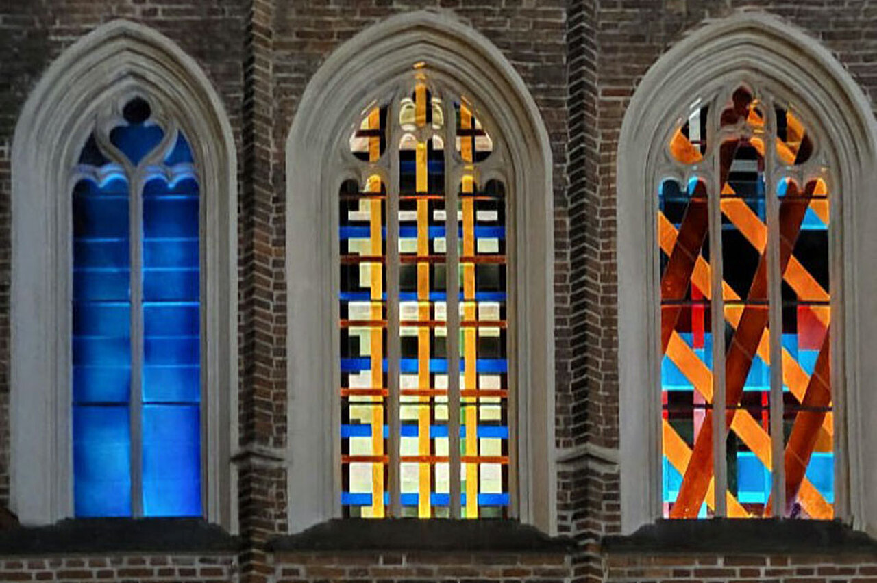 Abstrakt gestaltete Glasfenster in der Kirche St. Martin in Landshut mit farbigen geometrischen Formen in gotischen Fensteröffnungen.