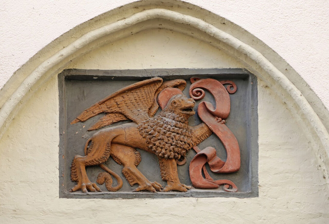 Historisches Wappenrelief mit geflügeltem Löwen an einer Gebäudefassade in der Landshuter Altstadt.
