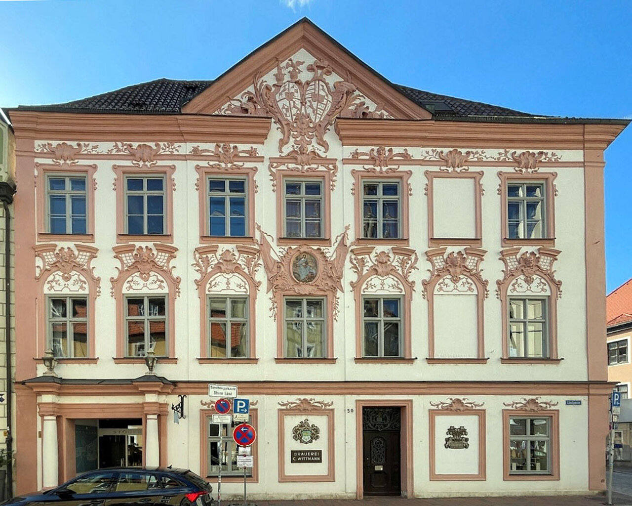 Historisches Gebäude in der Landshuter Altstadt mit aufwendig gestalteter Rokokofassade, Stuckverzierungen und Wappenschmuck.