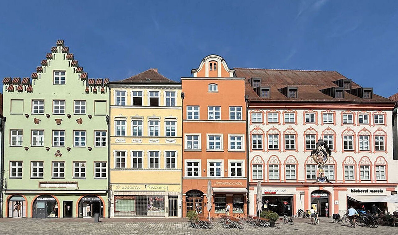 Der Landshuter Hauptplatz mit historischen Bürgerhäusern, farbigen Fassaden und dem Ludwigsbrunnen.