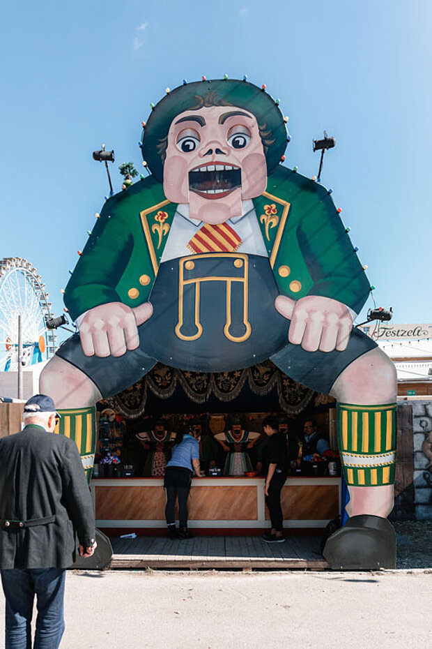 Historischer Wurfstand mit übergroßer Trachtenfigur auf dem Münchner Oktoberfest.